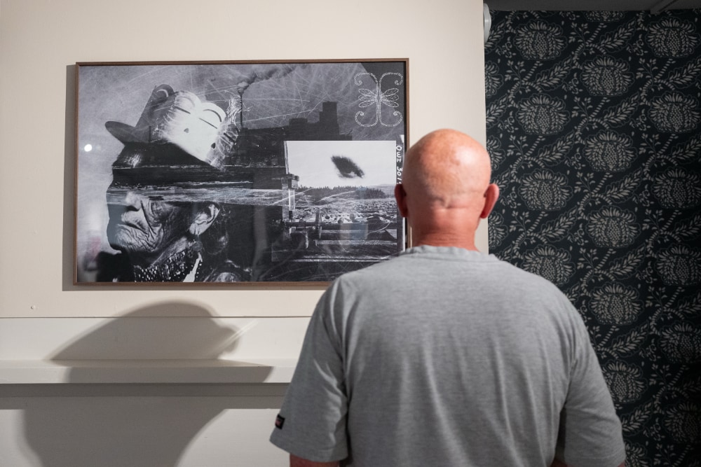 A visitor to the Wαpánahkəyak exhibit views a black and white collage.