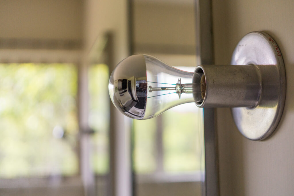 A closeup photo of a lightbulb on a wall.