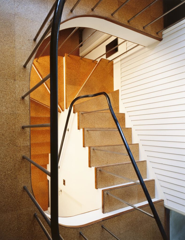 A spiralling staircase with light coming in from a large window.