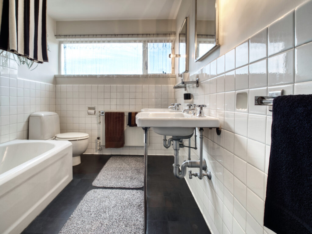 Master bathroom in Gropius House showing the sink, bathtub, and toilet. There is a window in the background.