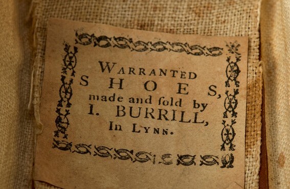 A label inside of a shoe reads, “Warranted shoes, made and sold by I. Burrill, In Lynn.” 