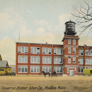 A hand-colored postcard showing a three-story brick building with many large windows and a water tank on top of a central four-story tower. Two horses and carts sit in front of the building, which is labeled Converse Rubber Shoe Co., Malden, Mass.
