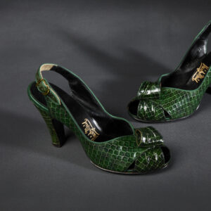 Two green, reptile skin patterned leather high heels with open sling backs and peep toes sit beside each other.