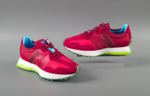 A pair of reddish sneakers, with an icy blue tread, a white and neon green sole, various shades of red and maroon on the upper, maroon laces, and a bright blue tongue and interior. The sides each feature a large capital N.