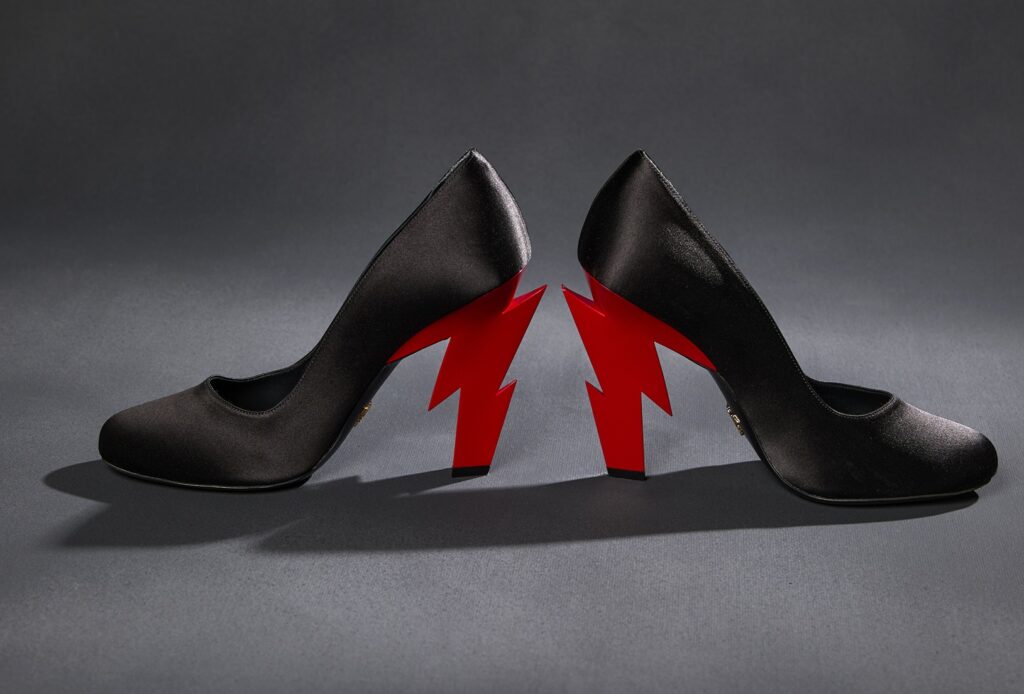 A pair of black satin high heels with jagged red lightning bolts as the heels.