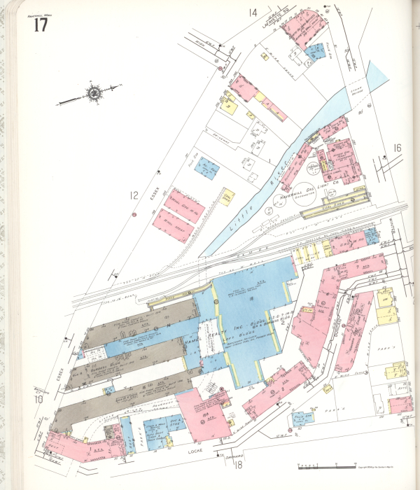 Un mapa multicolor muestra tres largos edificios industriales paralelos en la parte inferior izquierda. El río Little River baja desde la parte superior derecha y pasa por detrás de los tres edificios, serpenteando entre una serie de otros edificios históricos de ladrillo. 