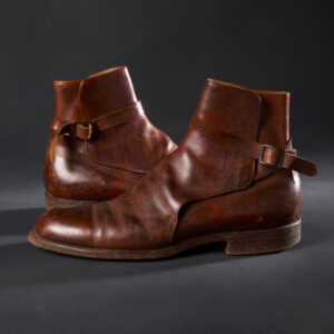 A pair of sturdy reddish-brown leather boots, with a buckled strap across each ankle.