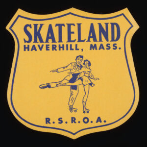 A large, yellow shield shape sticker with thin, blue outline and “Skateland, Haverhill, Mass.” above the cartoon drawing of a man and woman roller skating, and “R.S.R.O.A.” on the bottom.