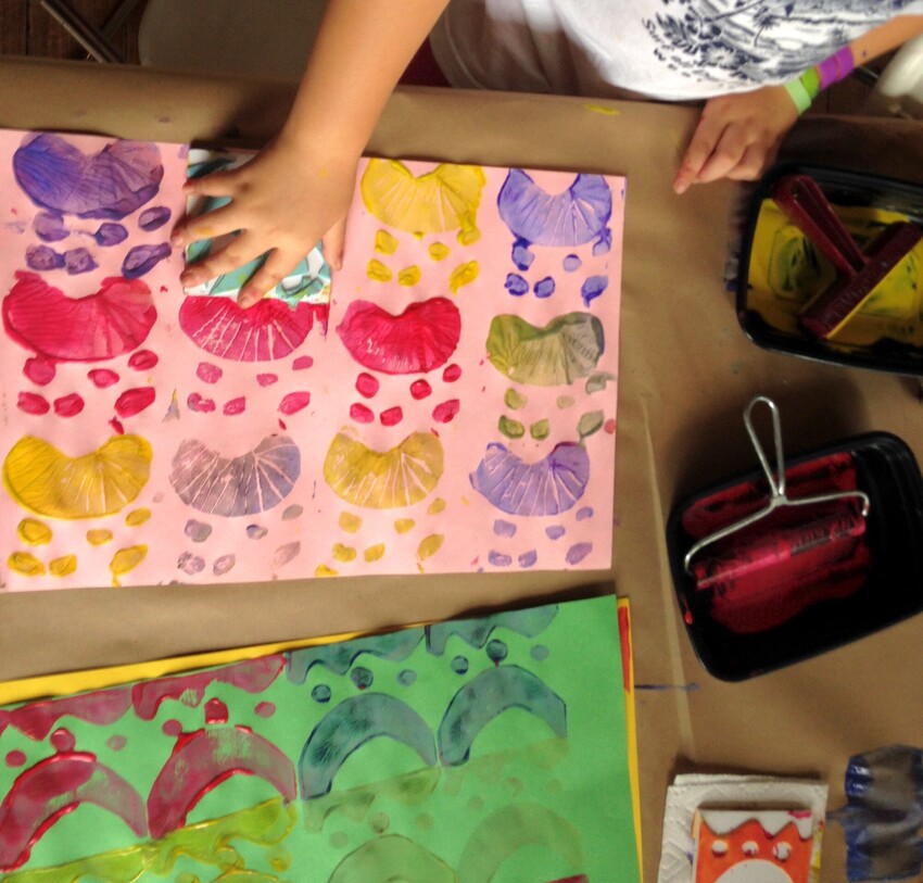 A child makes colorful printed artworks with a hand-held stamp.