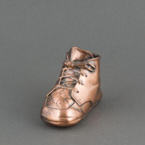 A bronze-coated baby shoe, with visible creases in the tongue under the tied shoelaces.