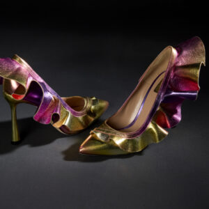 A pair of iridescent pink and gold heels with a dramatic leather ruffle descending along the outer edge of each shoe.