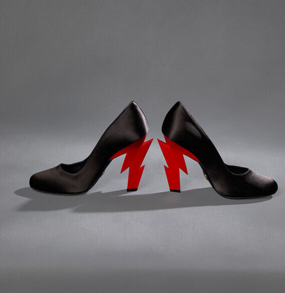 A pair of satin black high heels with a jagged red lightning bolt for each heel.