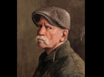 Three quarters profile potrait of a man wearing a coat and flat cap with a white mustache looking at the viewer.
