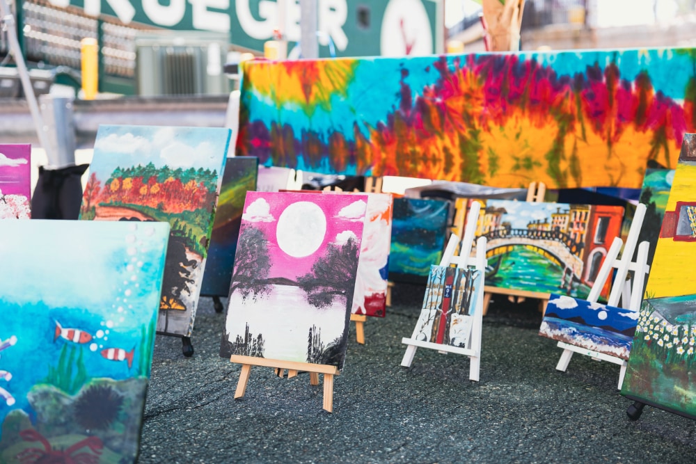 Easels set up with a number of paintings of different sizes.