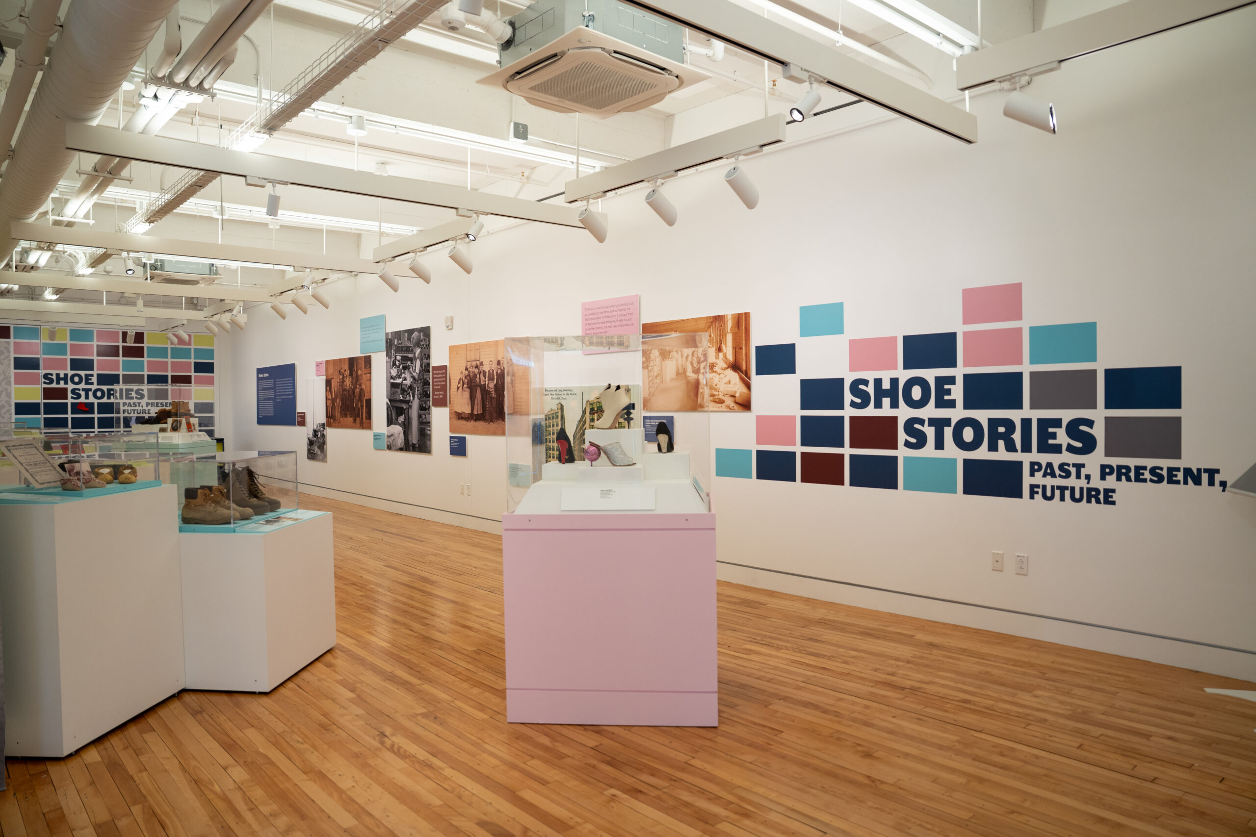 A photo of part of the Shoe Stories exhibition. The walls are shown with signage and images and some shoes are visible.