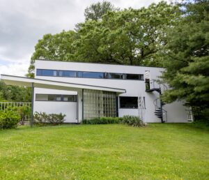 An exterior photo of Gropius House showing green grass and tree leaves.