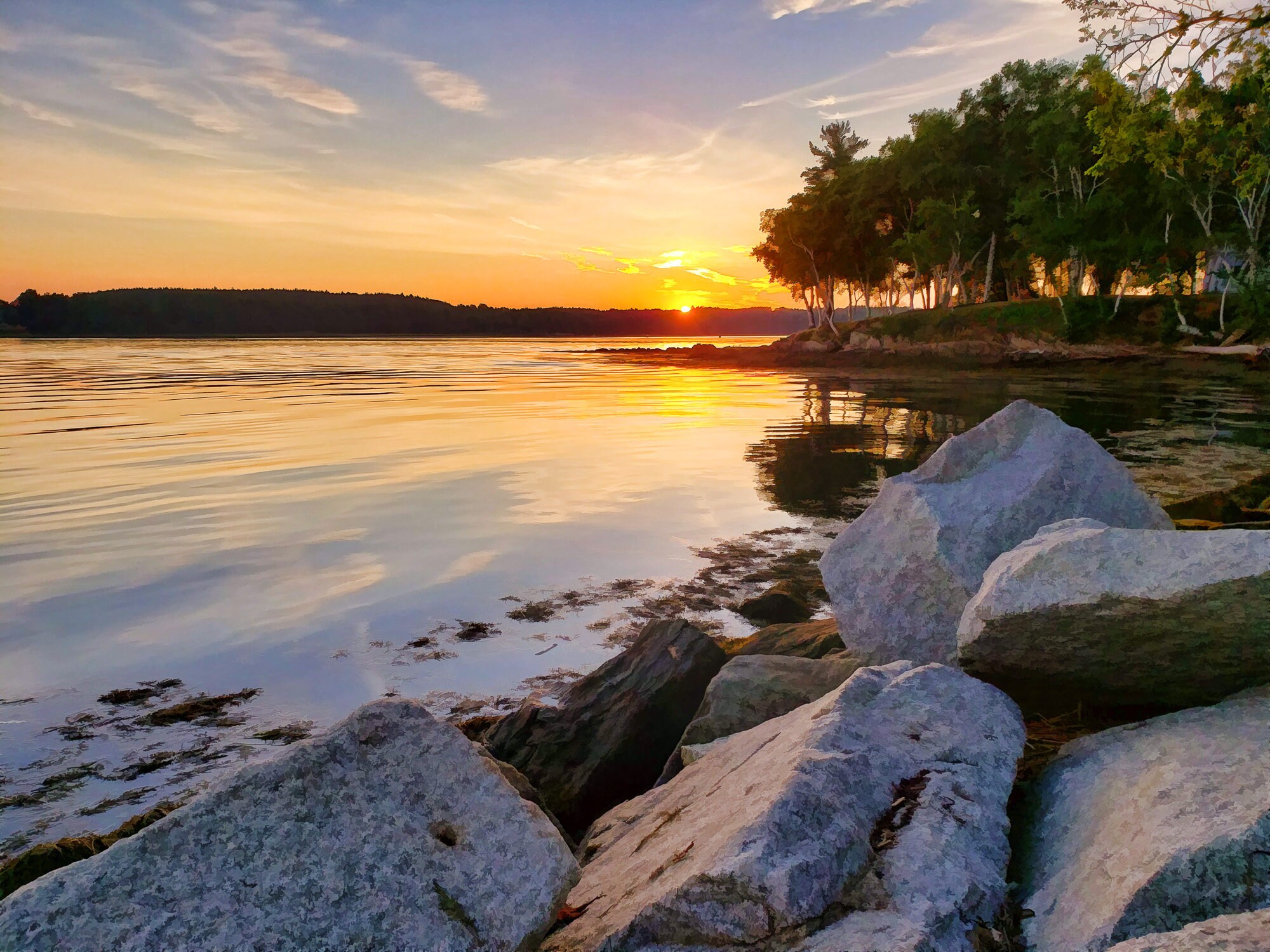 Rocky ocean shoreline in foreground sun setting in the background