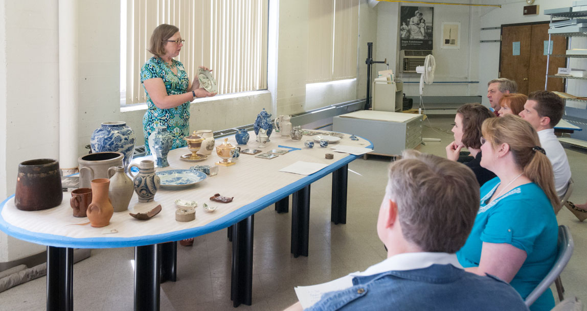 Participants and staff members of the Program in New England Studies (PINES) 2014 examine and interact with collection items. Groups viewed furniture, textiles, and ceramic items before touring the 8th floor photo studio and conservation lab.