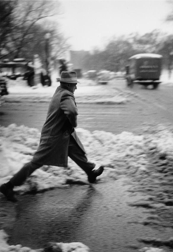 Man jumping over large puddle on the street