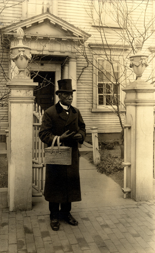 Man (Edward Cassell) stands in front of Nichols House, Salem, Mass. holding a basket. c. 1907
