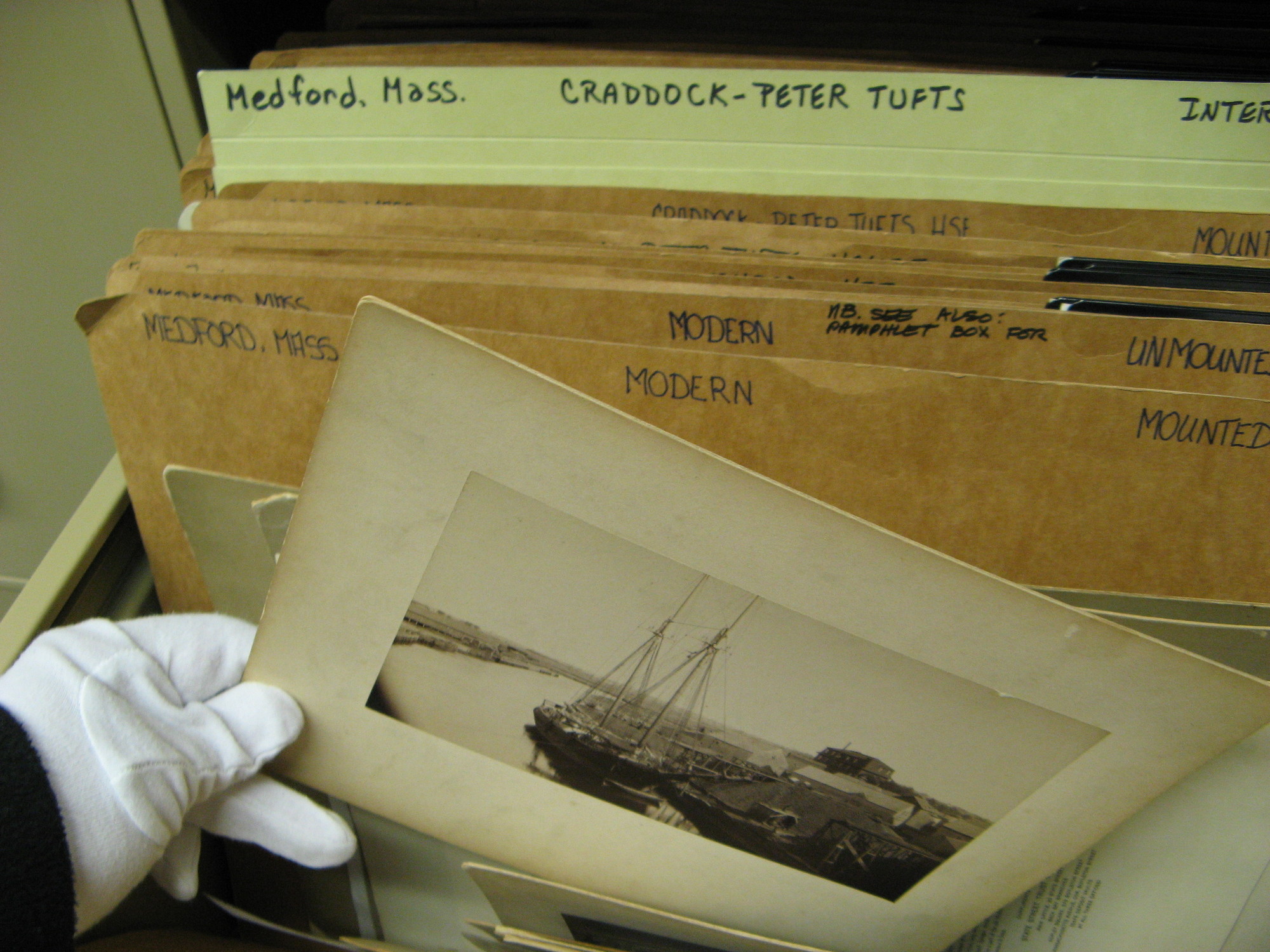 Gloved hand taking archival photograph out of file box.