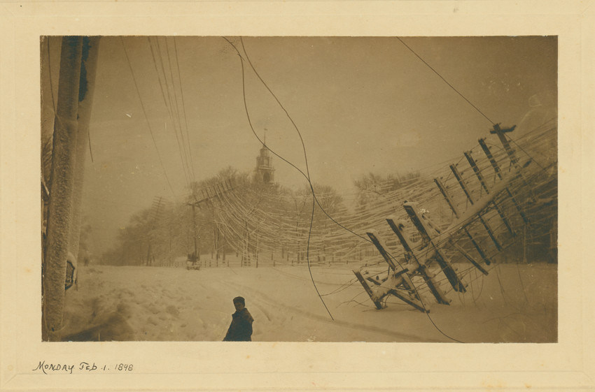 Roxbury in the winter with a figure in the foreground by a downed telephone pole. The First Church in Roxbury can be seen in the background.