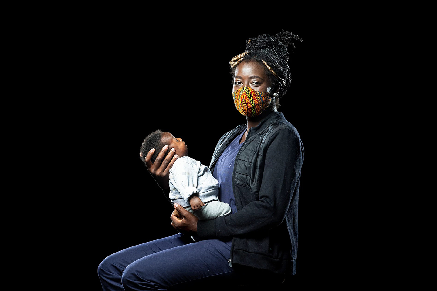 Portait of woman holding baby and wearing a face mask during the COVID-19 pandemic.