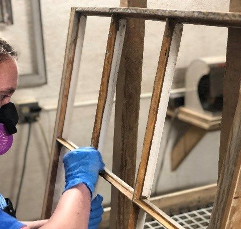 A conservator restores a window from Castle Tucker.