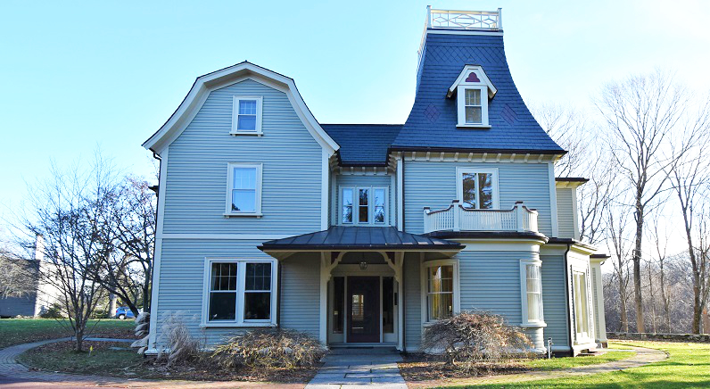 Historic house with light blue/gray paint and a mansard roof