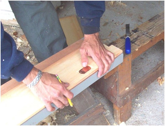 Carpenter marking wood plank with copper tag.