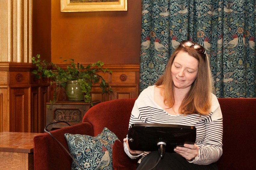 Woman seated on a sofa in a Victorian interior using a tablet.