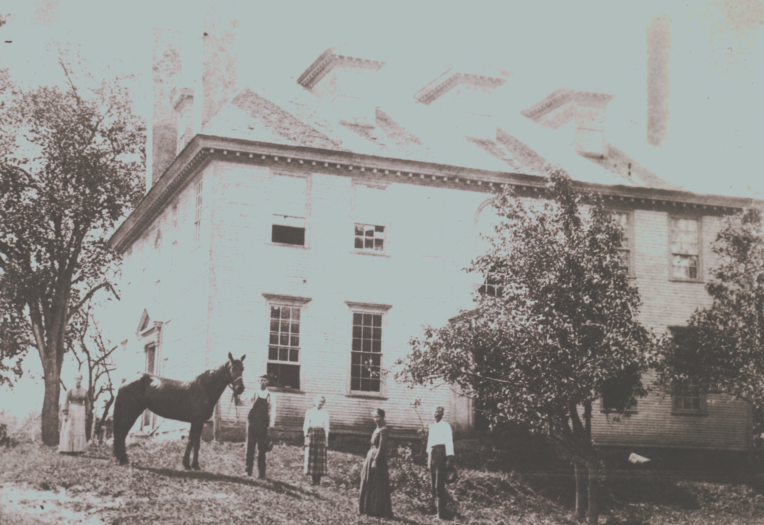 Black and white photo of two women and two men and a horse, standing on the lawn at Hamilton House