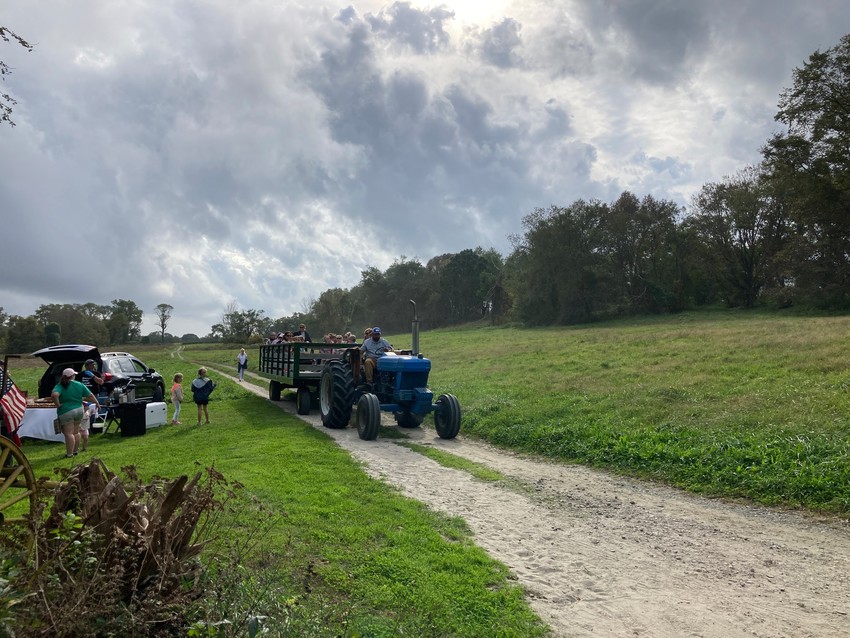 Farmer on tractor pulling a hay wagon down a drive