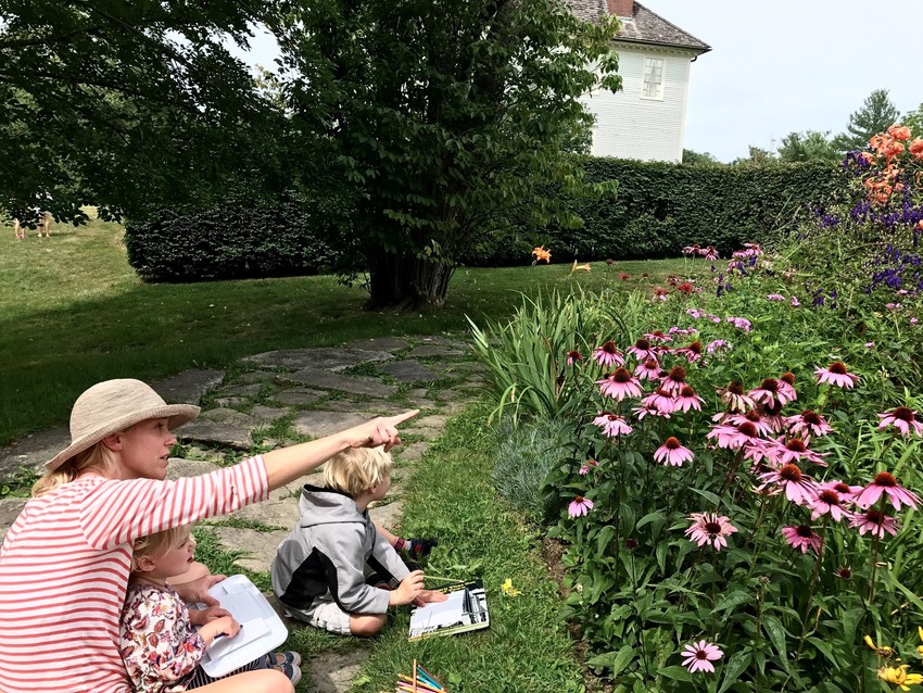 Mother ad 2 children in a perennial garden enjoying a summer day.