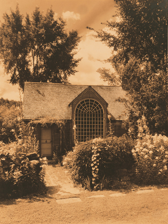 Sepia toned photo of garden cottage with large half round window