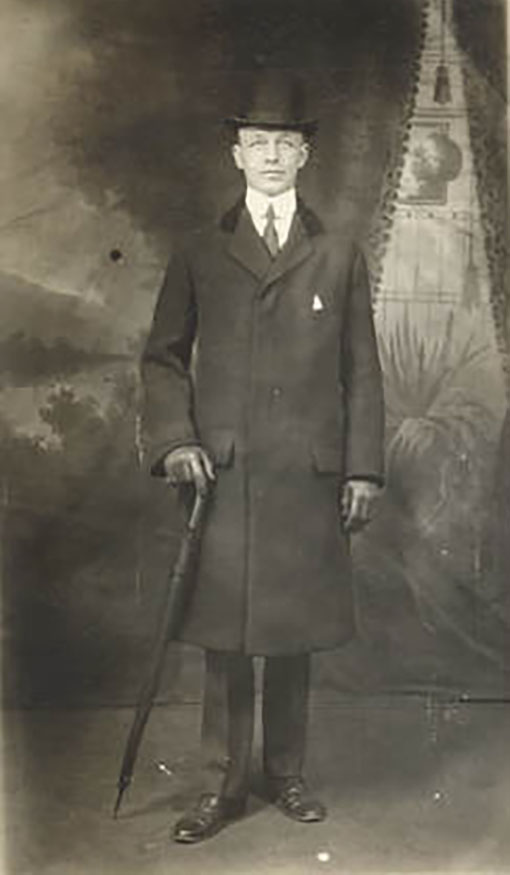 Portrait of man wearing top hat and overcoat, carrying an umbrella
