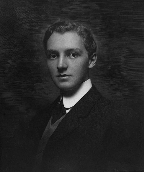 Formal black and white picture of young man with dress suit and high collar.