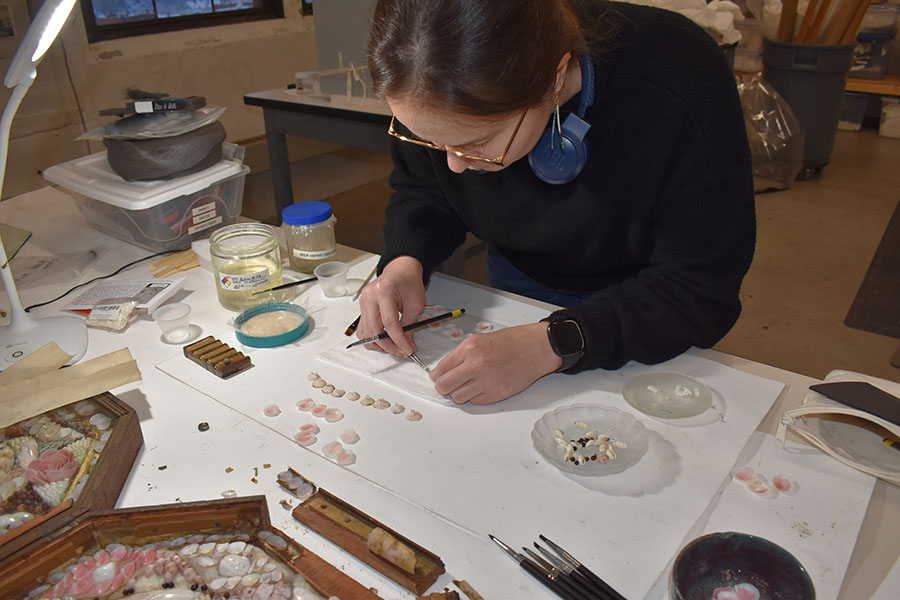 Person work to re-adhere shells in a piece of artwork