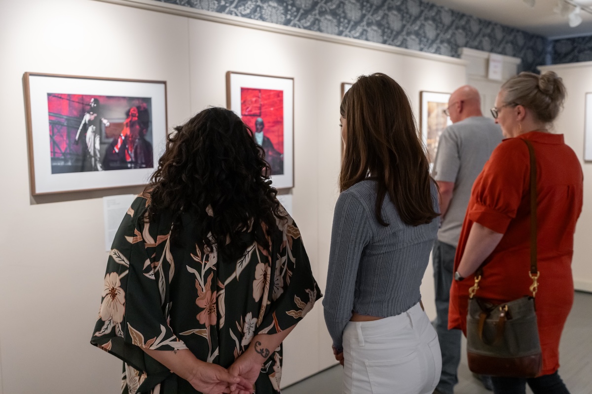 Four people look at art handing on a wall.
