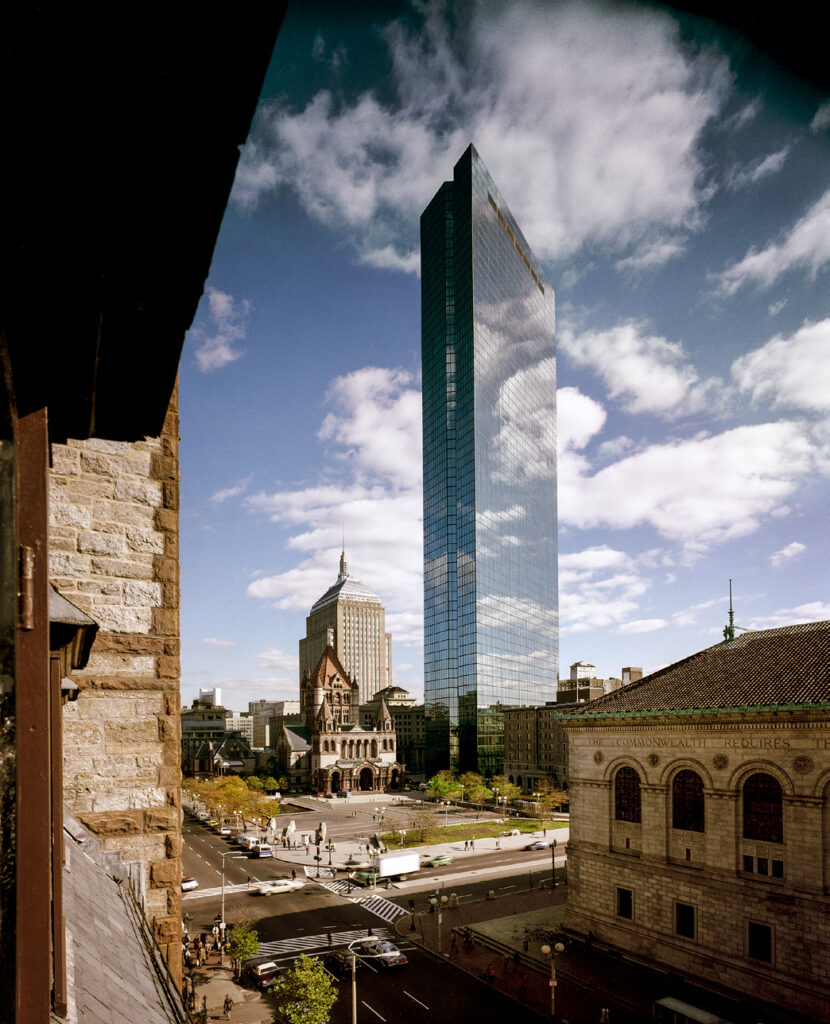 Urban landscape with a tall glass skyscraper and historic buildings.