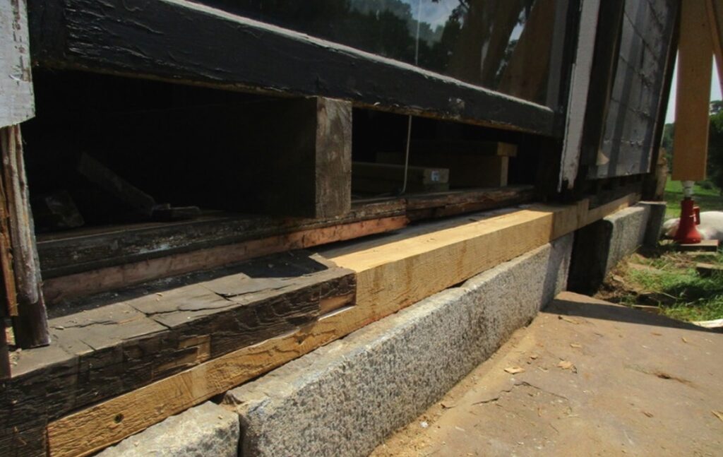 Construction site showing a building foundation with stone blocks and wooden beams.