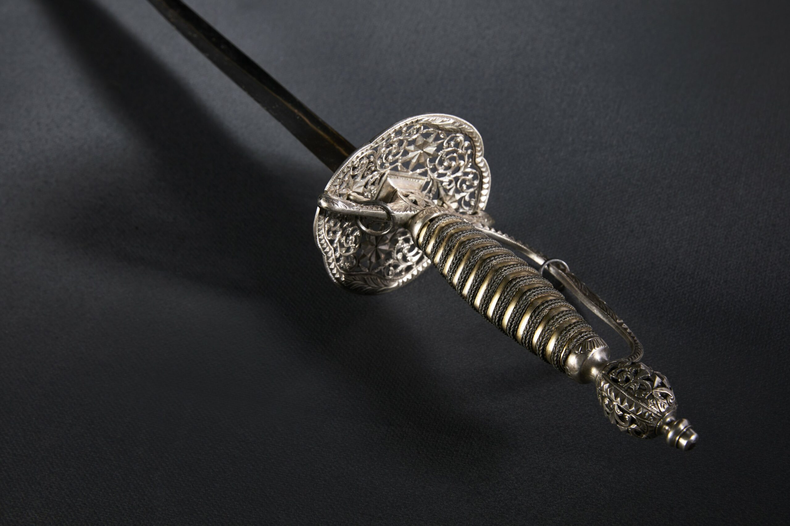 An ornate hilt of a sword lying on a dark background.