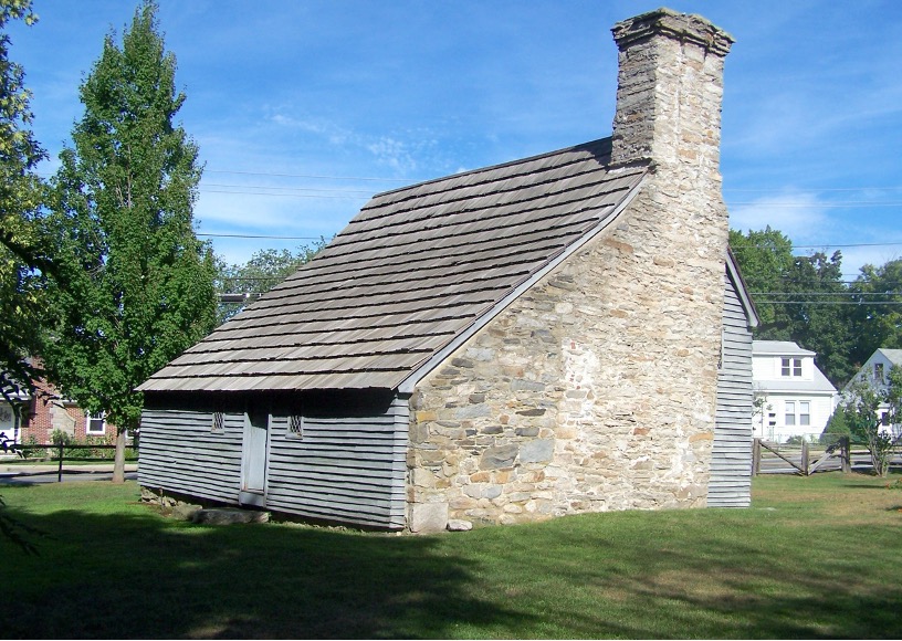 A small historic stone and wood house with a pitched roof and chimney.