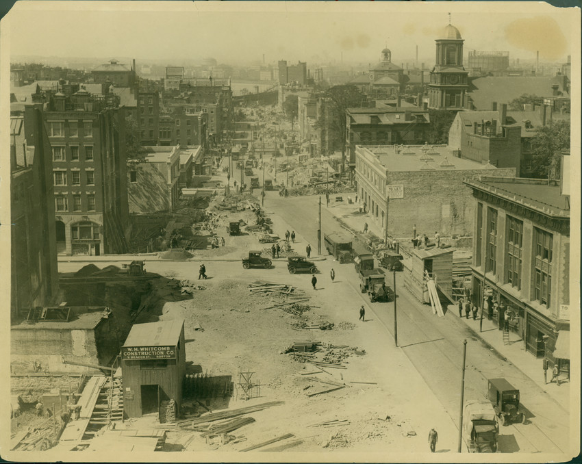 Historic urban street under construction with early automobiles and pedestrians. Transcribed Text: W. W. Whitcomb Construction Co.