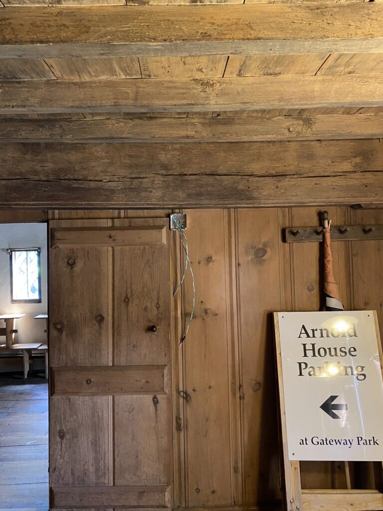 Interior with wooden beams, paneled walls, and a sign on a wooden stand. Transcribed Text: Arnold House Parking at Gateway Park.