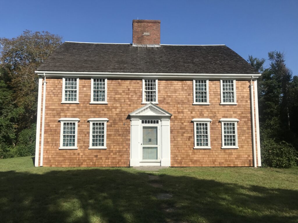 Colonial-style house with wooden shingles and white-trimmed windows.