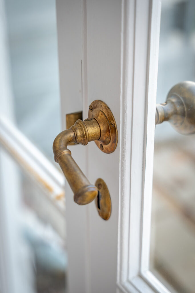 Close-up of a brass door handle on a white wooden door.