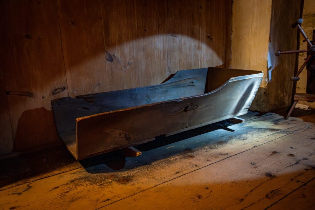Old wooden cradle on a wooden floor with a spotlight effect.