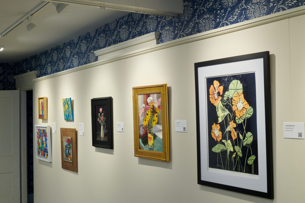 A gallery wall displaying various framed artworks with floral and abstract designs.