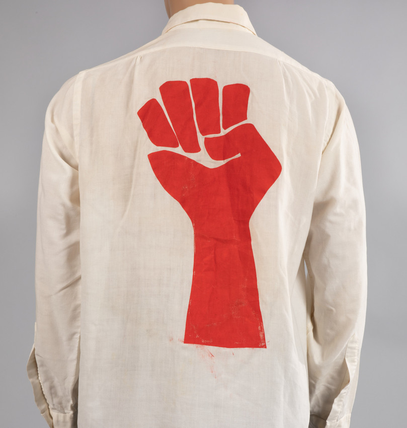 Raised red fist screen printed on an off-shite shirt.